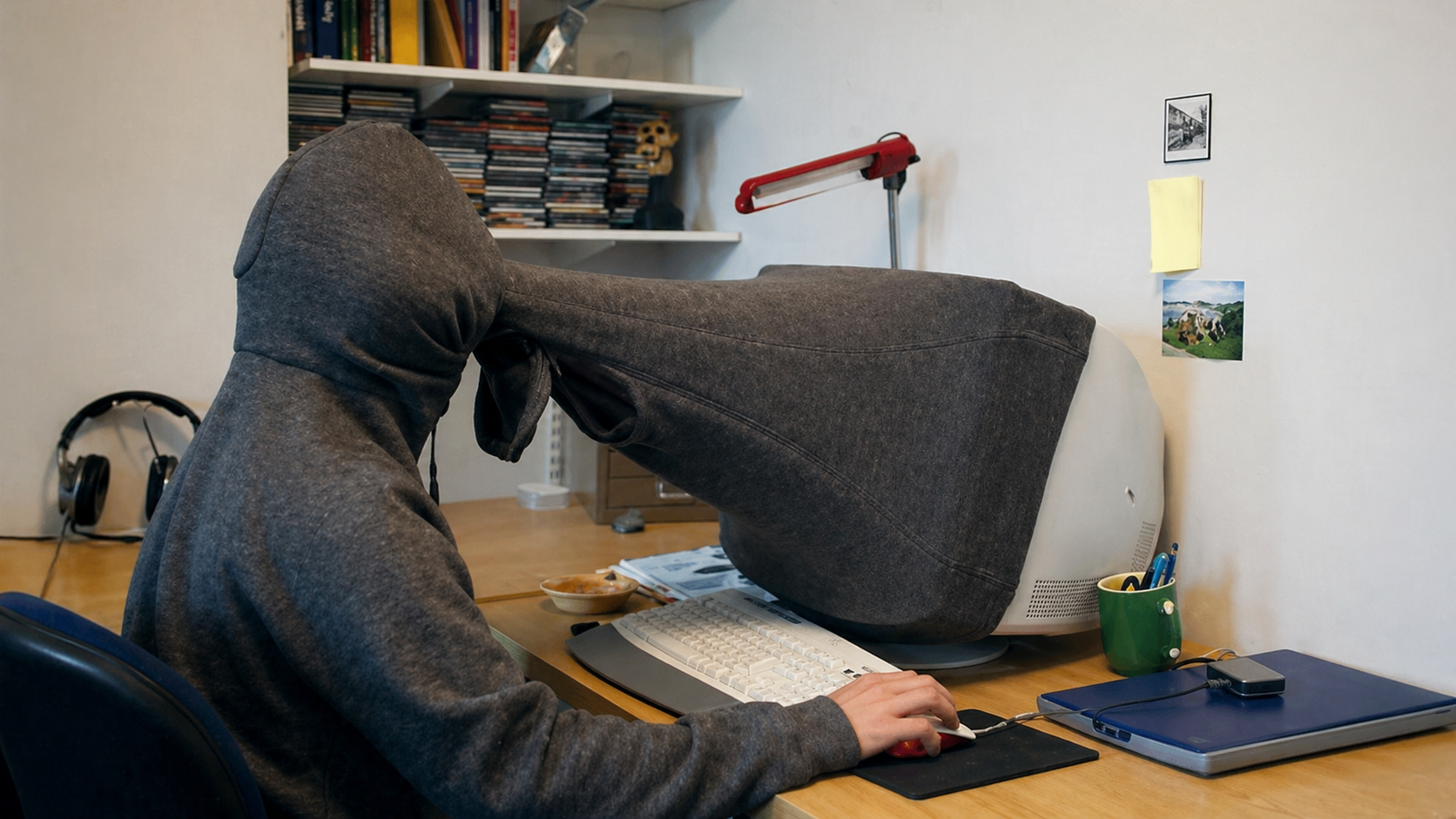 Person at a computer with a hoodie covering face